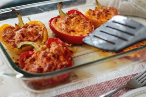 Preparing stuffed peppers, showcasing filling the bell peppers with a mixture of meats and grains.